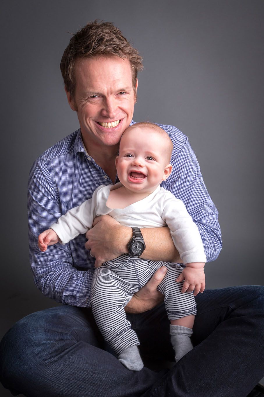Portrait of a baby boy and his dad in a studio with backdrop and lighting equipment